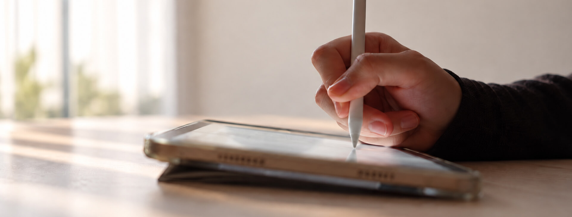 使用者手持 Apple Pencil 在桌面上的 iPad 螢幕進行書寫