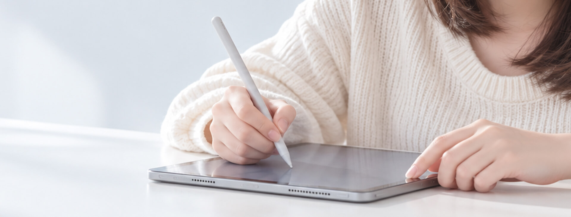 年輕女性在明亮桌面使用 Apple Pencil 於 iPad 螢幕上書寫