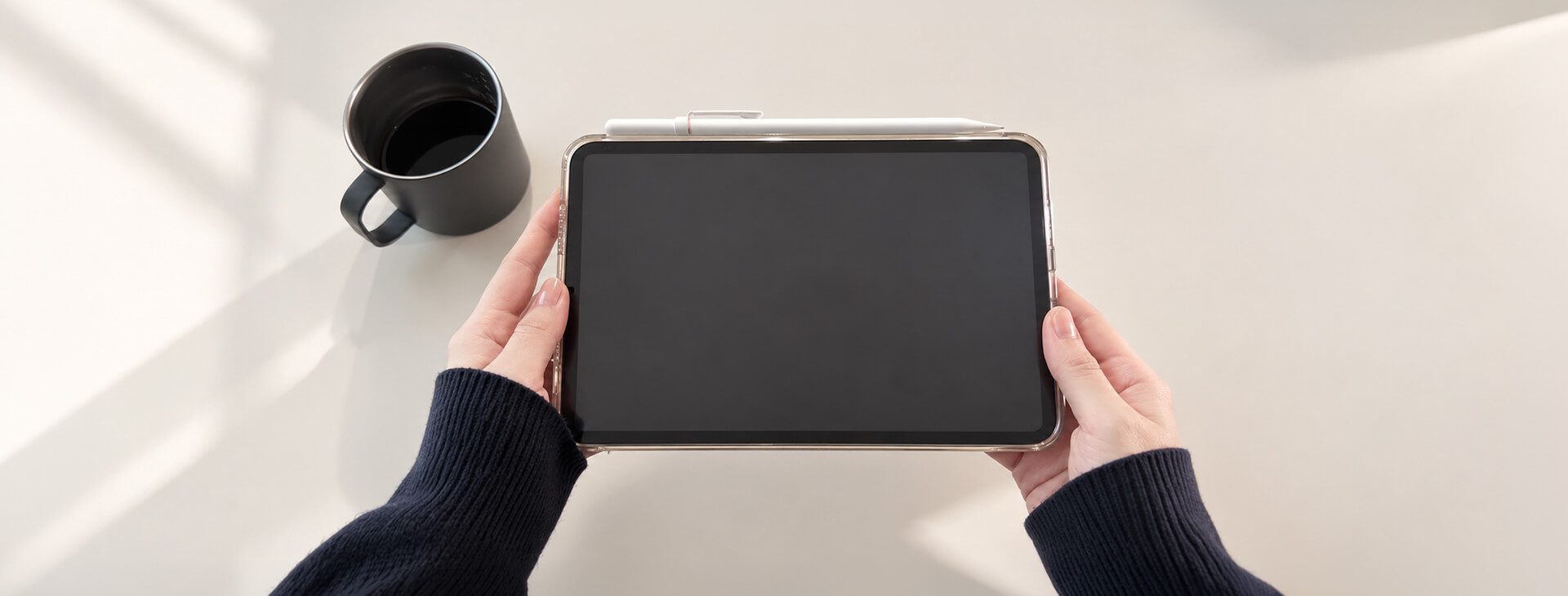 使用者雙手拿著 iPad，Apple Pencil 放置於平板上方
