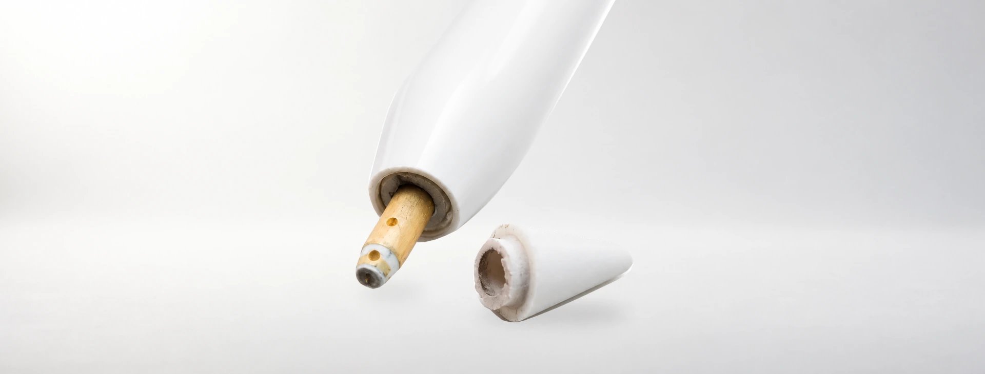 白色 Apple Pencil 前端露出金色柱體,旁邊放著根部破裂的白色筆尖外段